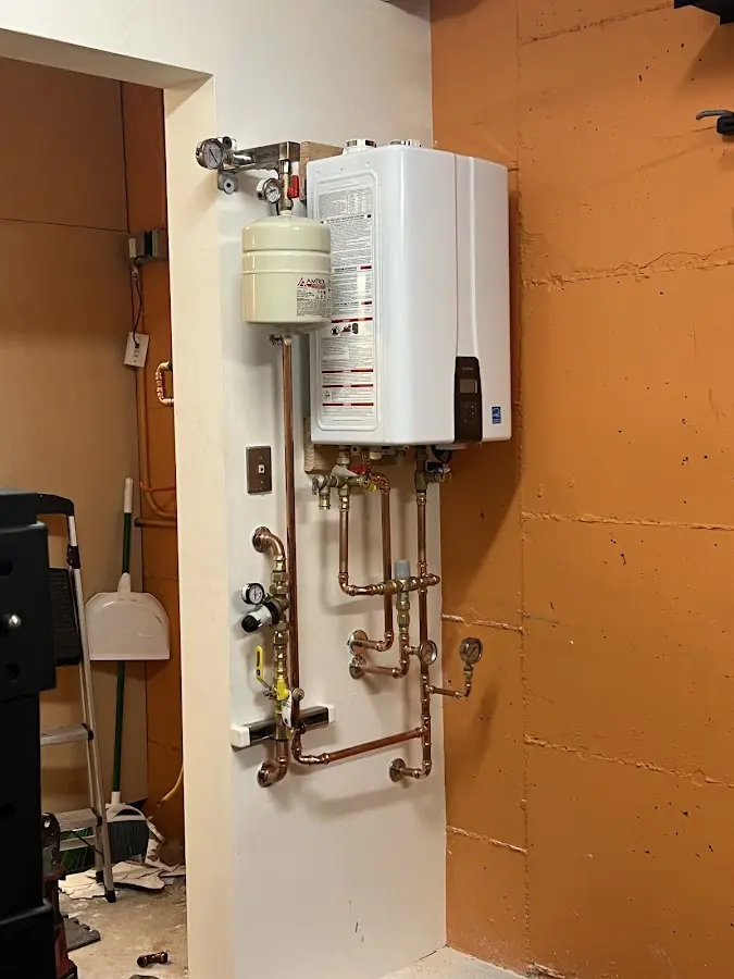 Plumbing technician inspecting water heater connections in New Boston